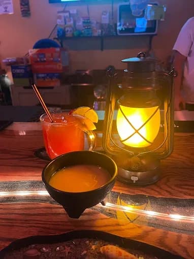 A kava shell and a red mocktail beside a lantern on the bar